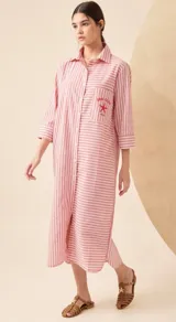 Vestido camisero largo a rayas verticales rosas y blancas, con cuello clásico, mangas 3/4 y bolsillo en el pecho con bordado de estrella de mar y texto.