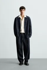 Blazer azul oscuro de denim, corte relaxed fit, con cuello de solapas de muesca, manga larga con puños abotonados, bolsillos de solapa en la cadera, abertura en el centro de la espalda y cierre frontal con botones.