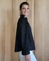 Blusa color beige con cuello con volados, mangas largas abullonadas con puños elásticos y cierre con botones en la parte delantera.