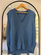 Chaleco azul de hilo con escote en pico, punto elástico en mangas y bajo, detalle de punto elástico y punto en ocho en la parte delantera.