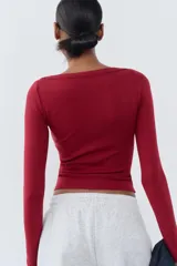 Camiseta negra de algodón con cuello barco y mangas largas.