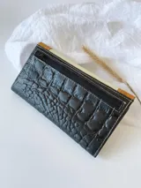Billetera triple de cuero color crema, marrón y negro, con cierre de broche y monedero externo.