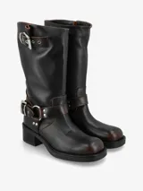 Bota de caña media de cuero negro, estilo biker, con caña arrugada y detalles de correas con hebillas metálicas plateadas en la parte superior y alrededor del tobillo. Posee un taco bajo y grueso.