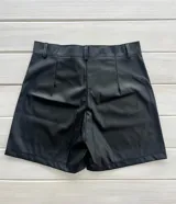 Short negro de cuero sintético, tiro alto, con botón y presillas para cinturón.