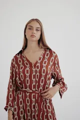 Vestido camisero color marrón con estampado de cadenas blancas, cuello camisero, mangas largas y lazo para ajustar en la cintura.