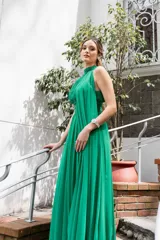 Vestido largo de gasa verde, con diseño trapeado y lazos en los costados del cuello.