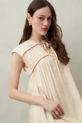 Vestido largo lila con escote con lazo, mangas cortas y frunces en el pecho.