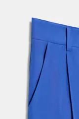 Pantalón negro de tiro alto con corte palazzo, bolsillos laterales y pliegues frontales. Cierre frontal con cremallera y botón.