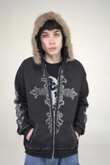 Campera con cierre frontal, capucha forrada con pelo sintético marrón y diseño de cruz grande con strass plateado en el frente. Presenta detalles de strass a lo largo de las mangas y en el borde inferior.