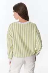 Buzo de poliéster a rayas verticales verdes y blancas en la parte superior y beige y blancas en la parte inferior, con cuello, puños y ruedo blancos. Estampado frontal con la frase "The Flowers Club" y la palabra "Petra".