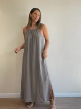 Vestido largo confeccionado en lino con cuello halter fruncido y tiras regulables. Presenta un diseño de silueta holgada con tajos laterales en el ruedo.