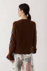 Sweater color gris claro con cuello redondo, mangas largas acampanadas y aberturas circulares en hombros y mangas con detalles de tela blanca.
