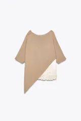 Top color beige de tejido de punto con mangas 3/4 y bajo asimétrico. Detalle de tejido combinado doble capa con encaje blanco en el ruedo.