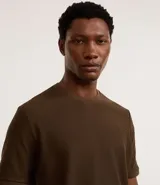 Remera de mangas cortas color crema, confeccionada con 50% algodón y 50% poliéster, con cuello redondo y tejido texturizado.