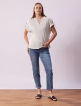Remera gris a rayas horizontales blancas, con cuello a la base y escote en V. Manga corta con presilla y botón.