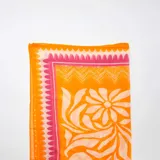Pareo de baño rectangular con estampado de flores y ondas en tonos naranja, blanco y rosa.