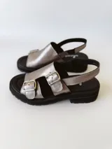 Sandalias de cuero color peltre con plataforma y suela track color negro. Presentan dos tiras anchas con hebillas plateadas y tira trasera ajustable.