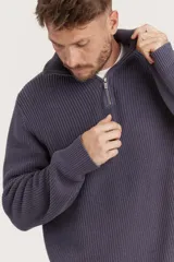 Sweater de punto color crema con cuello alto y cierre de cremallera parcial. Diseño de corte holgado y mangas largas.