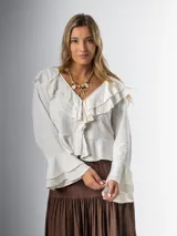 Blusa color crudo en lino rayón con volados, de mangas largas acampanadas y cierre frontal con botones.