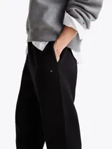 Joggers negros de felpa de mezcla de algodón con pierna cónica, cintura elástica con cordón, dos bolsillos laterales ribeteados y logo de Tommy Hilfiger bordado en el muslo.