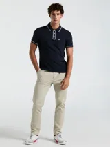 Polo de piqué azul marino de manga corta con cuello y borde de mangas con línea blanca. Tiene tapeta con tres botones blancos y bolsillo en el pecho con logo de pingüino bordado en blanco.