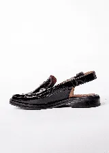 Mocasines color borgoña de cuero con punta fina, detalle de apliques metálicos y tira trasera con hebilla.