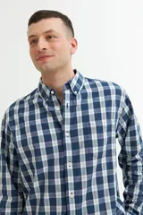 Camisa azul a cuadros grises de manga larga con cuello abotonado y bolsillo en el pecho.