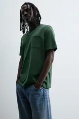 Camiseta verde oscuro de corte relaxed fit, cuello redondo, manga corta y bolsillo plastrón en el pecho.