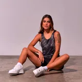 Musculosa deportiva negra con estampado de líneas diagonales blancas y logo de New York en el pecho.