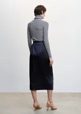 Falda midi cruzada color celeste, de tejido satinado y fluido, con abertura lateral, cierre lateral de cremallera, tiro medio, detalle fruncido y cierre de lazo lateral.