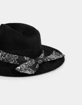 Sombrero negro de paja con ala ancha y cinta estampada de pañuelo en blanco y negro.
