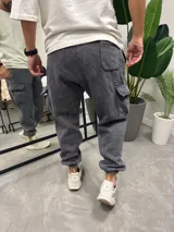Pantalón de jogging gris lavado con puños elásticos, bolsillos laterales tipo cargo y bolsillos traseros.