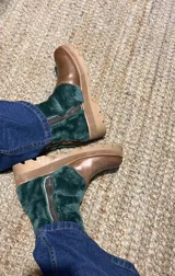 Botas de cuero con paneles de corderito, diseño con cierre lateral y suela resistente.
