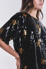 Remerón vestido negro con lentejuelas y estampado de estrellas doradas.