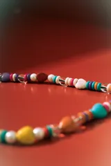 Collar corto de cuentas multicolores, con piedras naturales en forma de corazón y cuentas redondas de perla. Incluye cierres de mosquetón metálicos.