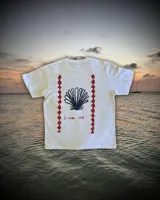 Remera blanca de algodón con corte oversize. Estampado en la espalda con una concha de mar azul, la frase "Summer time" en letra cursiva roja y dos líneas verticales con rombos rojos a los costados.
