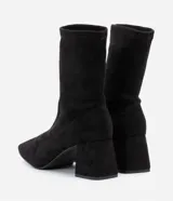 Bota de caña corta tipo media marca Satinato, color negro, con punta cuadrada y tacón grueso de altura media, confeccionada en material textil elástico sin cierre.