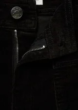 Pantalón de pana negro, de tiro alto y corte culotte. Presenta cierre de cremallera y botón, trabillas, dos bolsillos de parche delanteros y dos bolsillos de parche traseros.