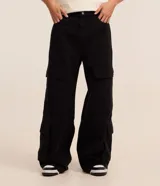 Pantalón de hombre de corte super baggy confeccionado en sarga de poliéster y algodón color negro, con bolsillos cargo laterales, cintura con trabillas y cierre de cremallera.