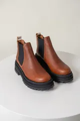 Borcegos negros de cuero vacuno con elástico lateral, suela track y tirador trasero.