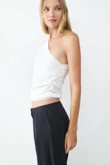 Top blanco de punto con diseño asimétrico y cuello tipo bufanda.