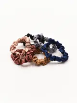 Set de cinco scrunchies de seda en colores rosa pálido, marrón, negro, gris y azul.