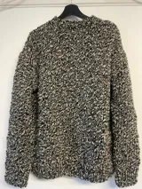 Sweater tejido a mano en lana color gris jaspeado, de calce holgado, con cuello a la base y puños ajustados.