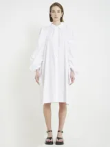 Vestido camisero blanco de algodón con cuello camisero, botones en la delantera, mangas ranglan fruncidas y abullonadas hacia el puño con tiras para ajustar.