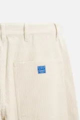 Pantalón de pana color crema, corte relaxed fit, con bolsillos frontales, bolsillos de parche en la parte trasera, bolsillos laterales en las piernas, trabilla multifunción y cierre con cremallera y botón.