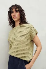Chaleco tejido color crudo con diseño calado, cuello redondo y mangas cortas. Corte holgado.