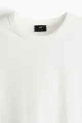 Remera blanca de algodón de peso medio, con cuello redondo ribeteado acanalado y bajo recto.