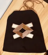 Top negro de gamuza con apliques geométricos de cuero en tonos beige, marrón y blanco.