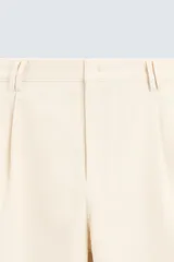 Pantalón negro de corte amplio, tipo balloon fit, con pinzas en la cintura, bolsillos laterales y traseros de ojal.