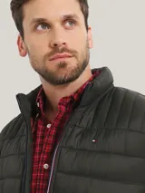 Campera acolchada verde militar de Tommy Hilfiger, con cuello alto, cierre de cremallera, dos bolsillos delanteros con cremallera y logo de Tommy Hilfiger bordado en el pecho.